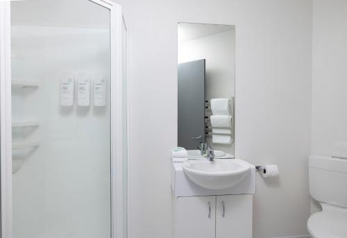 uma casa de banho branca com um lavatório e um espelho em Quest On The Terrace Serviced Apartments em Wellington