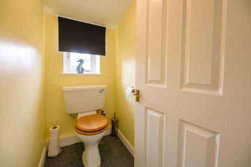 a bathroom with a toilet with a wooden seat and a window at No. 10 & 12 Bridge Street in Framlingham