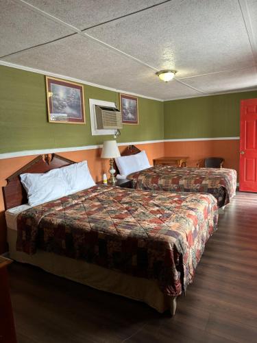 two beds in a hotel room with green walls at Sands Motel in Marianna