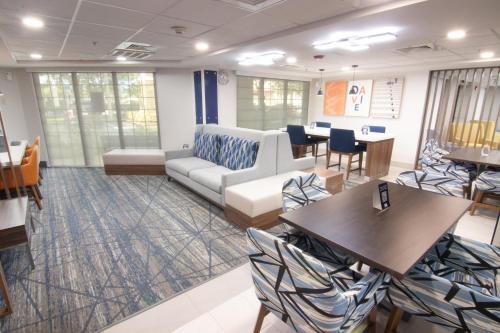 a waiting room with a couch and tables and chairs at Holiday Inn Express and Suites Fort Lauderdale Airport West, an IHG Hotel in Davie
