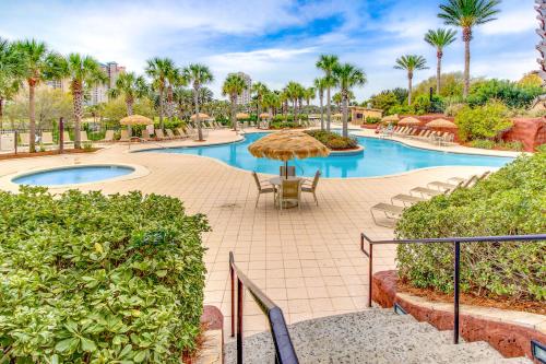a resort with a pool with chairs and umbrellas at Luau 6909 in Destin
