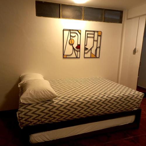 a bed in a room with two pictures on the wall at CASA AVILA - Apartamento amoblado 4 - Villa Alsacia in Bogotá