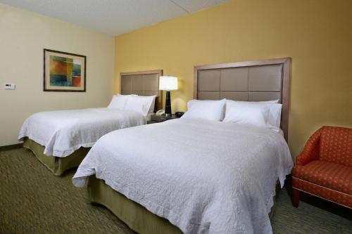 a hotel room with two beds and a chair at Hampton Inn Raleigh/Town of Wake Forest in Wake Forest