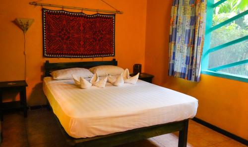 a bed with white sheets and pillows in a room at Cabinas Guarana in Puerto Viejo