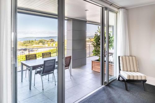 a dining room with a balcony with a table and chairs at Hilton Lake Taupo in Taupo