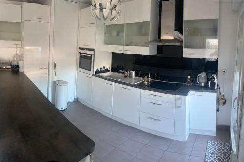 een keuken met witte kasten en een zwart aanrecht bij Appartement Aéroport Orly in Athis-Mons