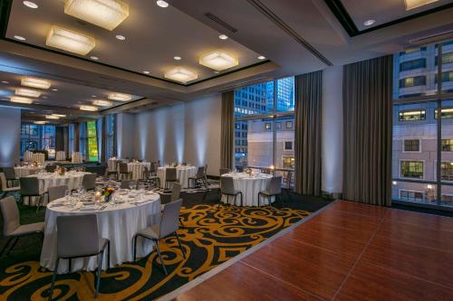 a restaurant with white tables and chairs and windows at theWit Chicago, a Hilton Hotel in Chicago