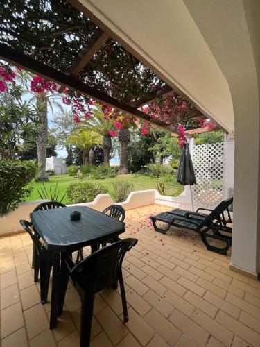 un patio con mesa, sillas y flores en Beautiful Villa with terrace & garden, en Ferragudo