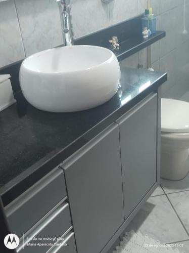 ein Badezimmer mit einem weißen Waschbecken auf einer schwarzen Theke in der Unterkunft Casa individual no bairro da Velha em Blumenau in Blumenau