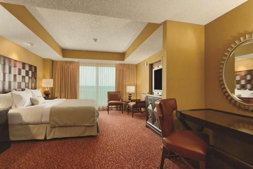 a hotel room with a bed and a desk and a mirror at Embassy Suites Murfreesboro - Hotel & Conference Center in Murfreesboro