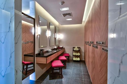 a bathroom with red stools and a vanity with mirrors at Hilton Nay Pyi Taw in Nay Pyi Taw