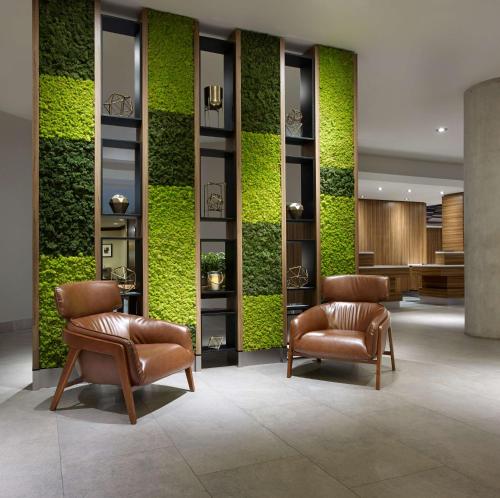 a lobby with two chairs and a green wall at Hilton Garden Inn Toronto Airport in Mississauga