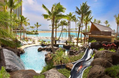 a resort pool with a waterfall and a water slide at Hilton Hawaiian Village Waikiki Beach Resort in Honolulu