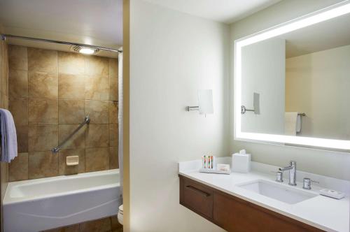 a bathroom with a sink and a tub and a mirror at Hilton Hawaiian Village Waikiki Beach Resort in Honolulu
