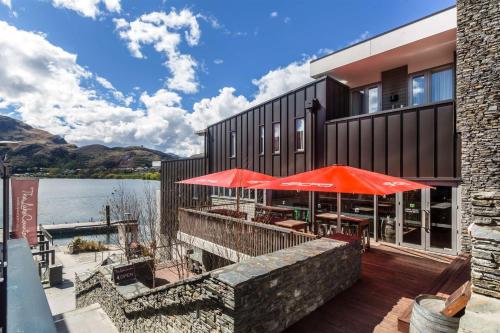 an outdoor patio with red umbrellas and the water at DoubleTree by Hilton Queenstown in Queenstown