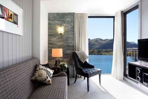 a living room with a couch and a large window at DoubleTree by Hilton Queenstown in Queenstown