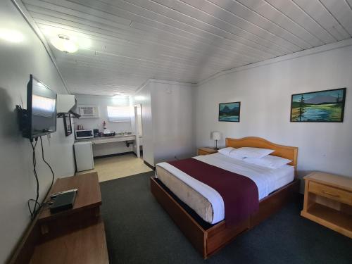 een slaapkamer met een bed en een flatscreen-tv bij Sundowner Motel in Cache Creek