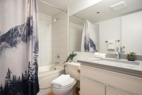 a bathroom with a toilet and a sink and a shower at Prime Village Ski In Ski Out Location by Harmony Whistler in Whistler