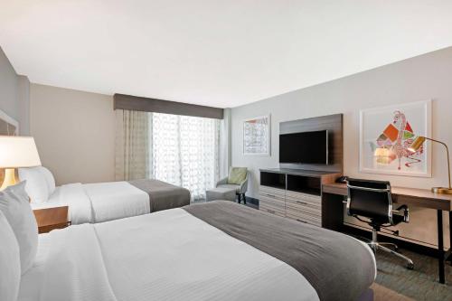 a hotel room with two beds and a desk at Best Western Plus Daytona Inn Seabreeze in Daytona Beach
