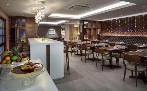 a restaurant with tables and chairs and a bar at Hilton Cambridge City Centre in Cambridge