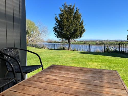 a table and chairs on a porch with a view of a lake at Riverside Bliss in Clive
