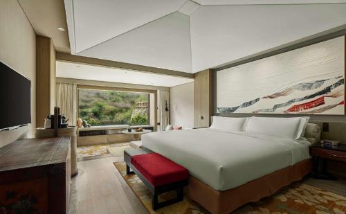 um quarto com uma cama grande e uma janela grande em Conrad Jiuzhaigou em Jiuzhaigou