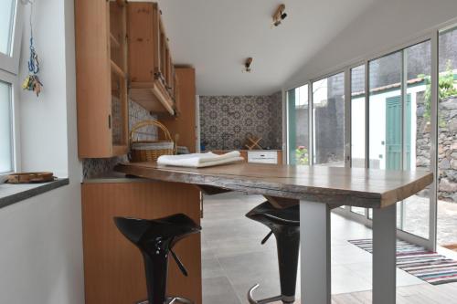 una cocina con mesa de madera y taburetes negros en Vale dos Ilhéus en Machico