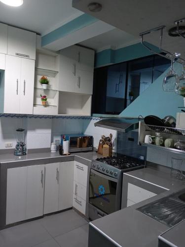 a kitchen with white cabinets and a stove top oven at Apartamentos ARCEMIR in Ayacucho