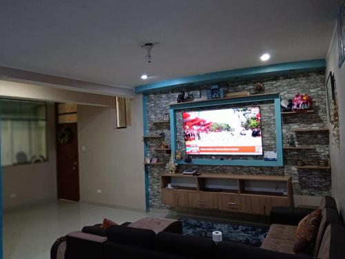 a living room with a stone wall with a flat screen tv at Apartamentos ARCEMIR in Ayacucho