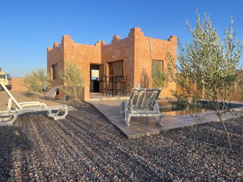 una casa en el desierto con dos sillas en una cubierta en Dar KOUJANE villa avec piscine, 