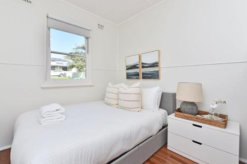 Rathmines的住宿－The Little Lake House at Rathmines waterfront on Lake Macquarie，白色的卧室设有床和窗户