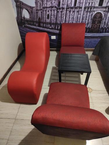dwa czerwone krzesła i stół w pokoju w obiekcie Sillary Sede Paucarpata w mieście Paucarpata