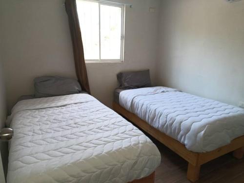 Duas camas num pequeno quarto com uma janela em Casa Villa (facturamos) em Los Mochis