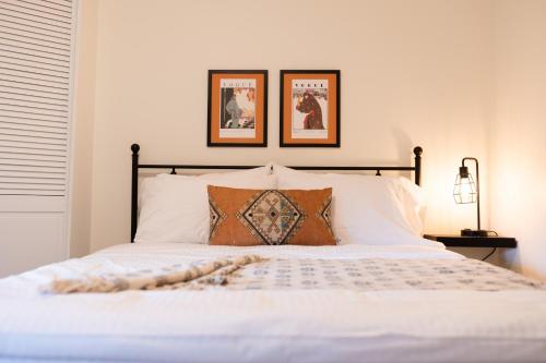 - une chambre avec un lit blanc et deux photos sur le mur dans l'établissement Charming Kelowna Haven with Hot Tub, Parking, Pet-Friendly Bliss, à Kelowna