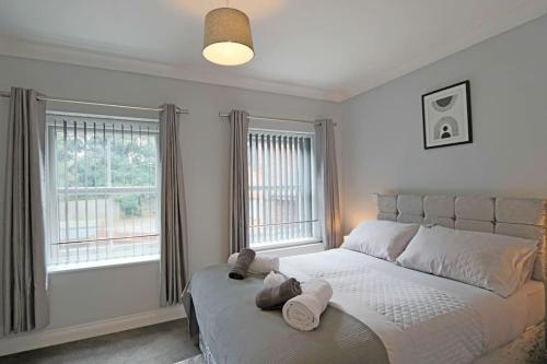 a bedroom with a large bed with two windows at Deluxe & Modern 2bed House in Derby