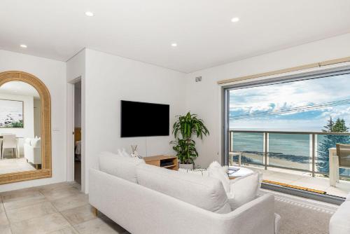 a living room with a white couch and a large window at Beach Break in East Ballina