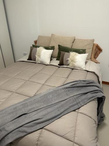 Una cama grande con almohadas encima. en Departamento temporal de 1 dormitorio en Neuquén