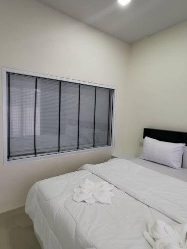 a white bedroom with two beds and a window at NST Boutique เอ็นเอสทีบูทีค in Ban Pak Phun