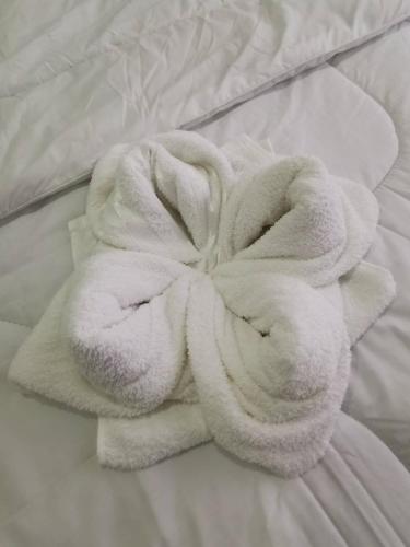 a white towel laying on top of a bed at NST Boutique เอ็นเอสทีบูทีค in Ban Pak Phun