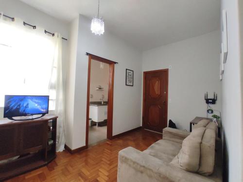 a living room with a couch and a flat screen tv at Apartamento completo no centro in Teresópolis