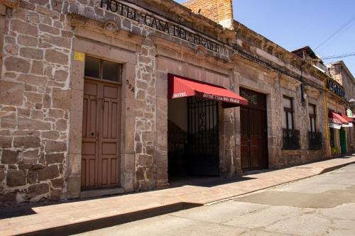 a brick building with a red awning on a street at Hotel Casa del Fraile in Morelia