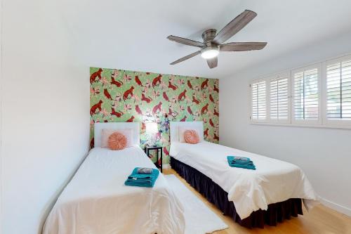 two beds in a room with a ceiling fan at Mesquite Retreat in Phoenix
