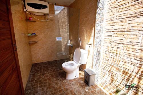 a bathroom with a toilet and a stone wall at Yasa Homestay in Nusa Penida