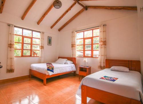 a bedroom with two beds and two windows at Eco Hacienda Roman in Machu Picchu