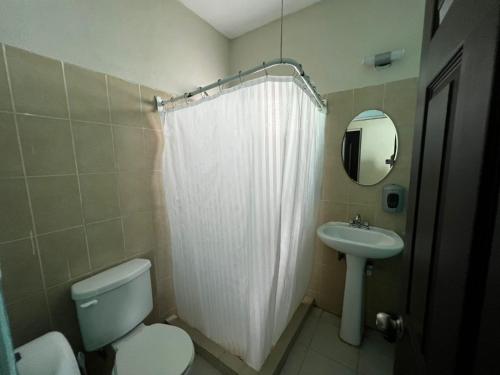 uma casa de banho com um WC e um lavatório com uma cortina de chuveiro em Casa con alberca y jardín en Cancún em Cancún