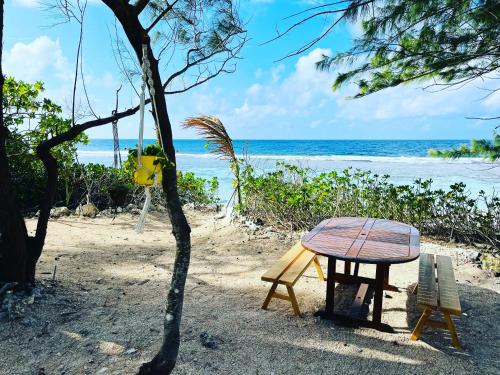 a table and chairs on a beach with the ocean at Bungalow KURA in Moorea