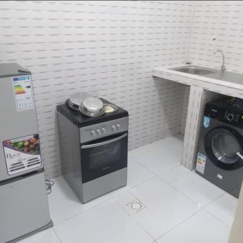 a kitchen with a stove and a sink and a washing machine at Bienveillance in Saint-Louis