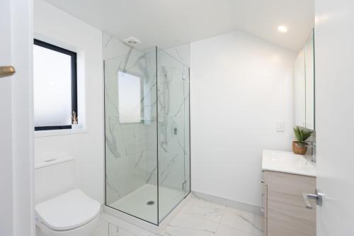 a bathroom with a shower with a toilet and a sink at Beachfront Haven in Christchurch