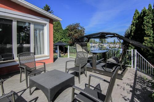 un patio con sillas, mesa y cenador en La Perle Rose du Lac-St-Jean, en Roberval