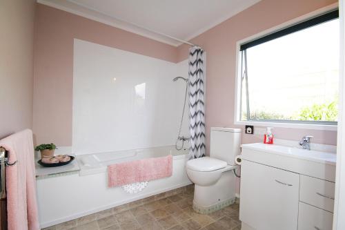 a bathroom with a toilet and a sink and a window at Bella Park - New Plymouth Holiday Studio in New Plymouth